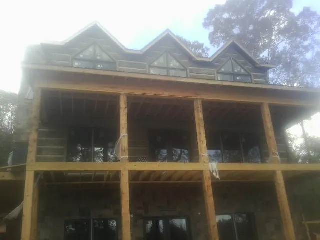 Dormers and porch framing on a large log home under construction — Roof Coating work by our crew in Fort Laramie