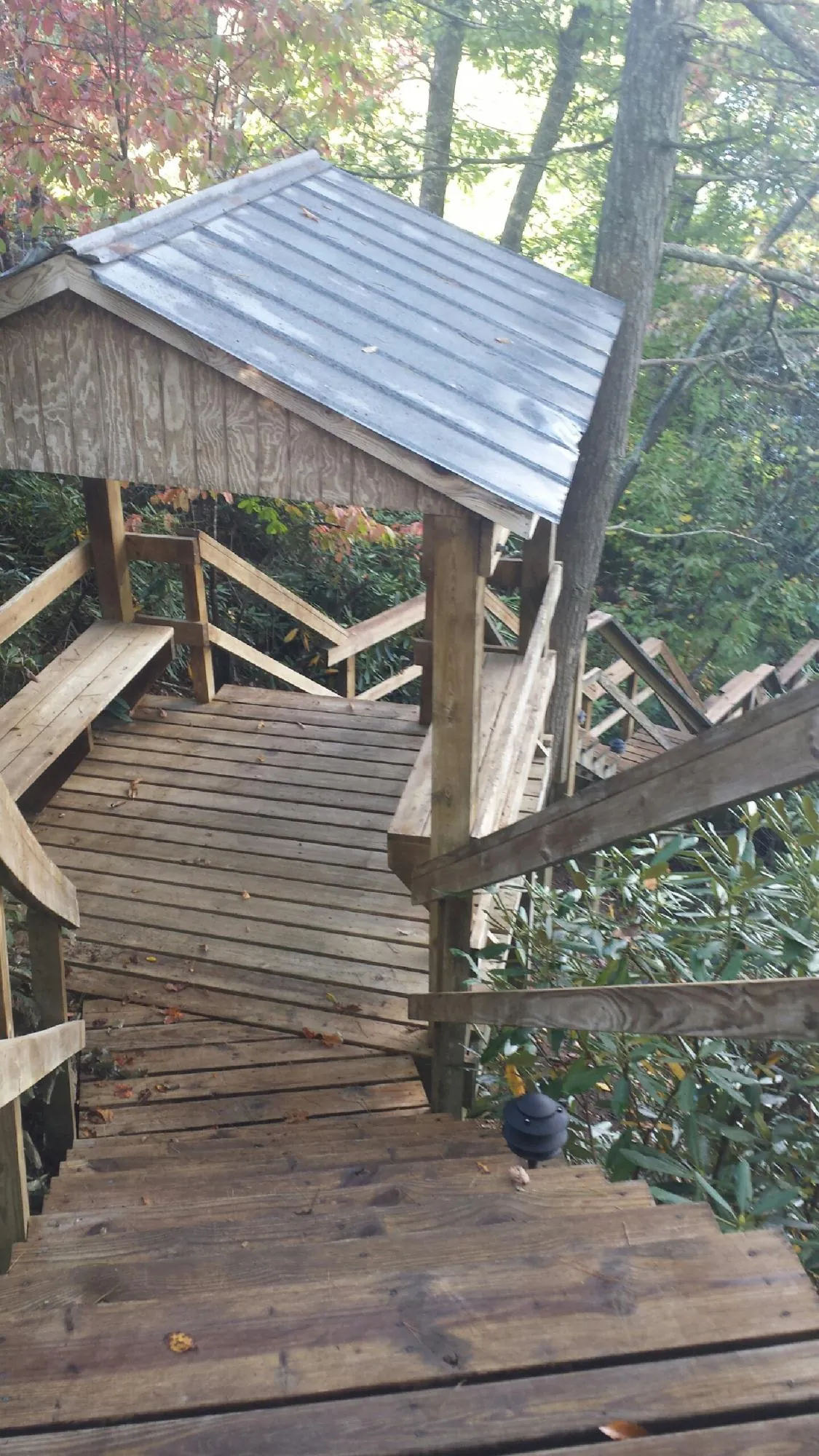 Metal roofed shelter over wooden steps on a wooded walkway — Skylight Repair & Installation work by our crew in Fort Laramie