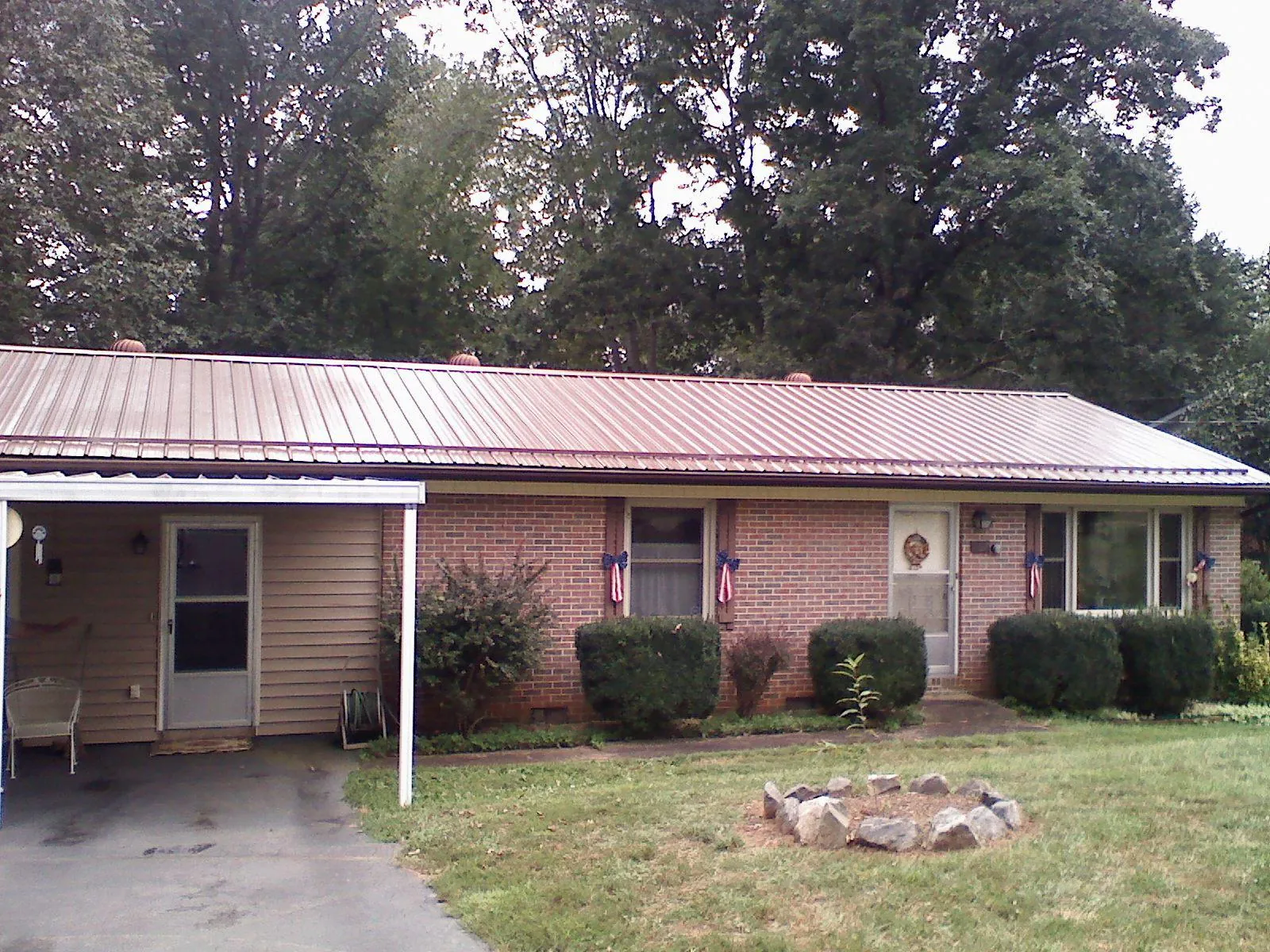 Bronze metal roof and carport on a brick ranch home — Roof Repair work by our crew in Fort Laramie