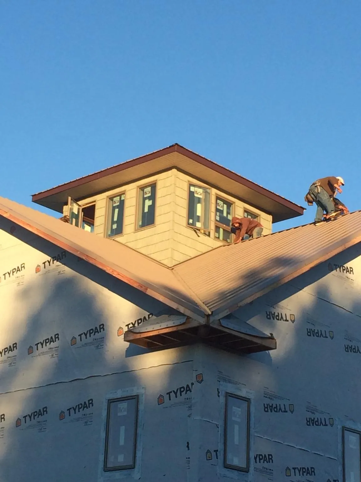 Roofers working around a rooftop cupola on a new metal roof at sunset — Roof Waterproofing in Fort Laramie by Roofing Brothers